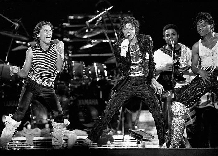 Band performing on stage with dramatic lighting, showcasing vibrant costumes and instruments, related to wild rumors.