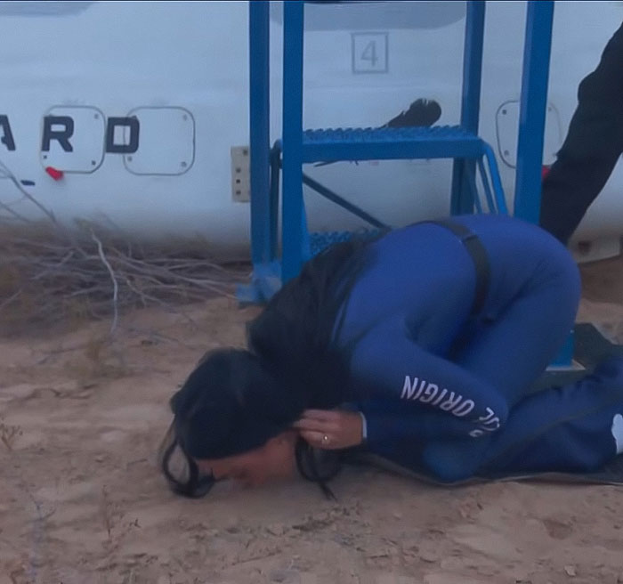 Person in a Blue Origin jumpsuit crouching on the ground, sparking conspiracy theories about the flight.