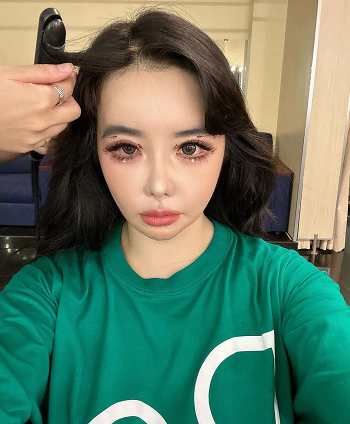 K-Pop star with drastic transformation amid plastic surgery rumors, wearing a green shirt, hair styled.