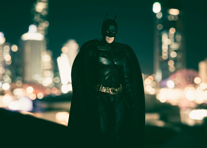 A superhero stands on a rooftop at night, city lights in the background, embodying unrealistic movie moments.