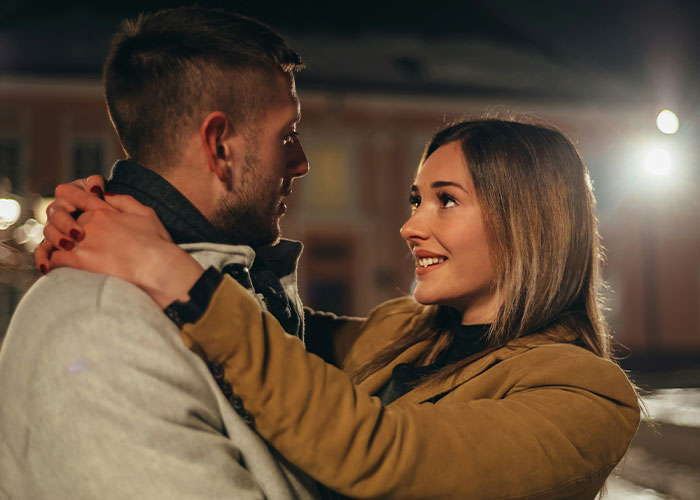 A couple embracing outdoors at night, smiling and sharing a moment, illustrating cheat code relationship advice for men.