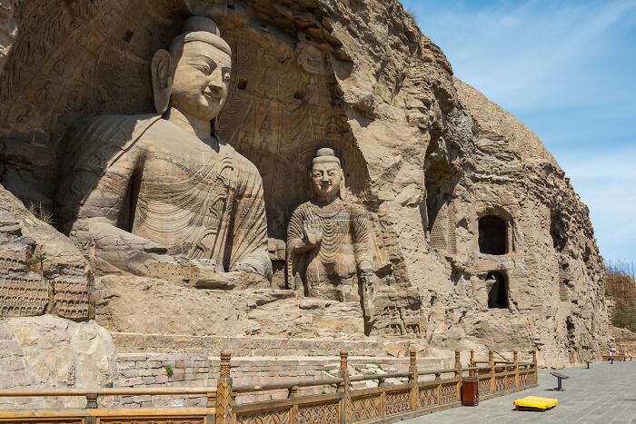 Ancient rock carvings of Buddha sculptures, an architectural wonder, under a clear sky.