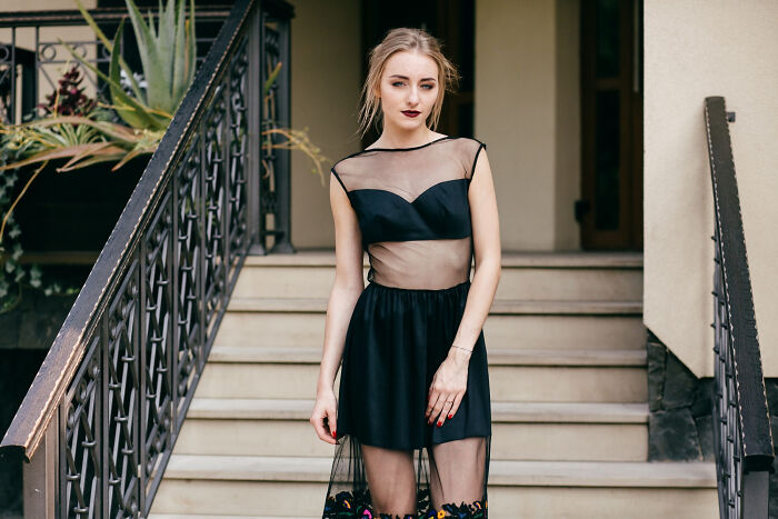Woman in a stylish black dress on stairs, challenging common assumptions about women.