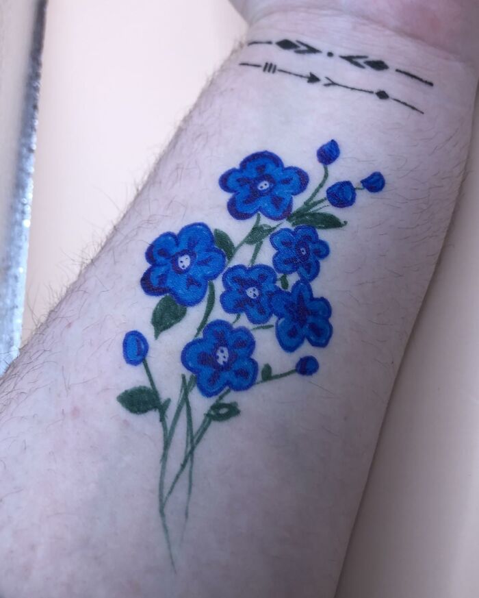 Temporary tattoo with blue flowers on a forearm, part of a festival survival kit from Amazon's Festival Shop.