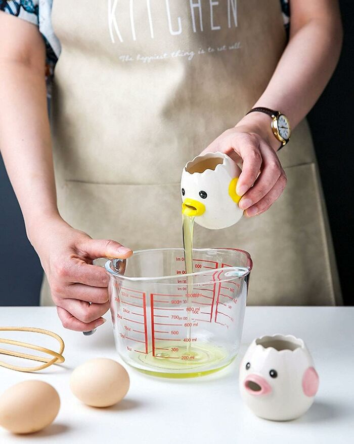 Person using a quirky egg separator from Amazon finds to pour egg whites into a glass measuring cup while baking.