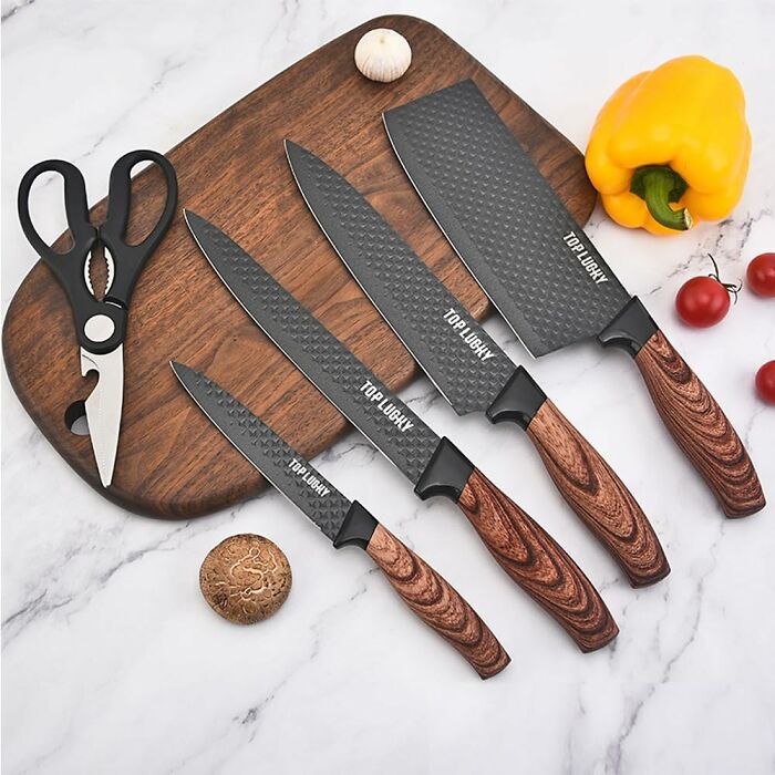 Trendsetting treasures: Knife set with dark blades and wooden handles on a cutting board, with kitchen scissors and vegetables.