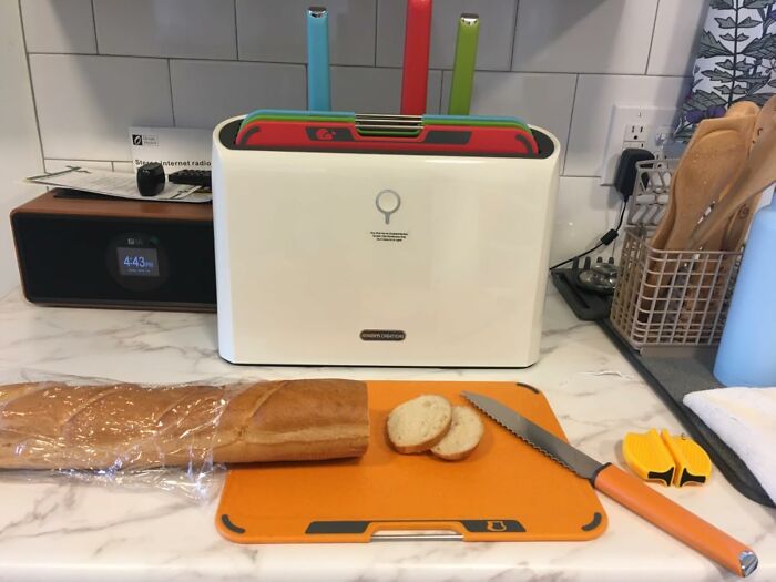 Kitchen setup with cutting board, bread, knife, and a set of colorful chopping boards, showcasing a most-wished-for item on Amazon.