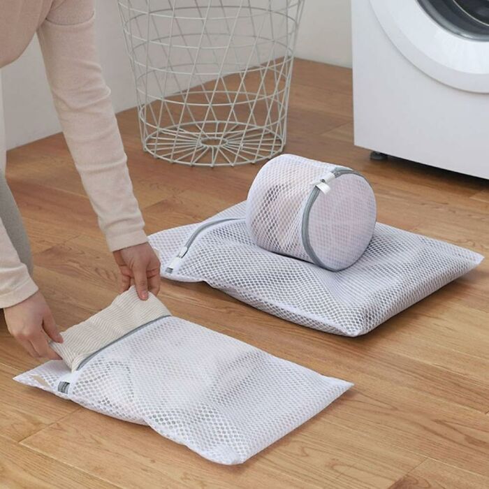 Mesh laundry bags from an Amazon haul find, used for organizing delicate clothes on a wooden floor near a washing machine.