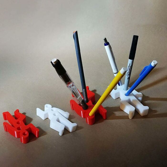 Pen holders shaped like figures, organizing work supplies on a desk.