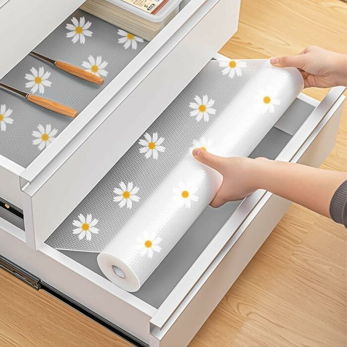 Hands placing floral-patterned drawer liners inside a kitchen drawer, highlighting affordable Amazon haul kitchen deals.