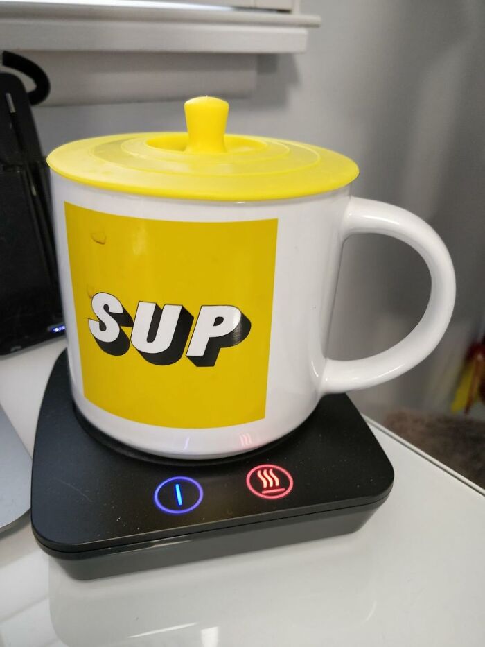 Smart home mug warmer with yellow lid on digital heating pad.