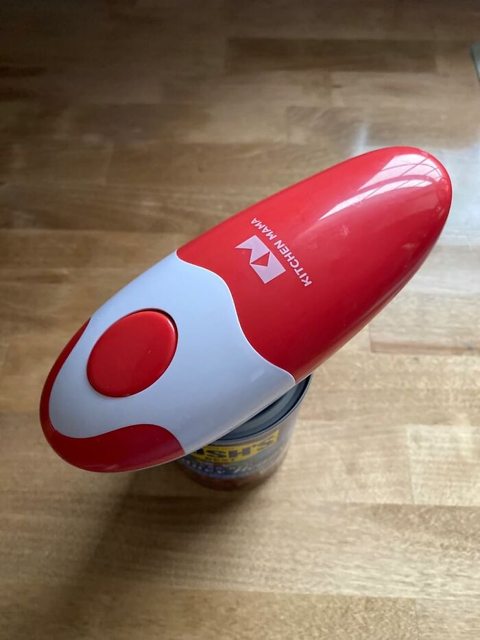 Red and white electric can opener in use on a can, showcasing one of Amazon's popular movers and shakers.