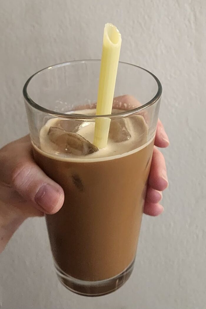 A hand holding iced coffee with a pasta straw, appealing to millennial tastes.