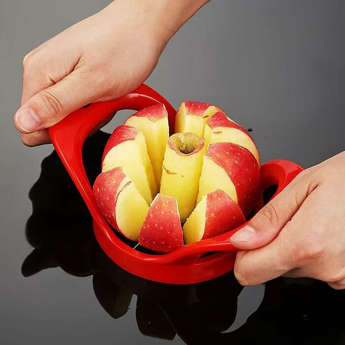 Hands using a red apple slicer corer to cut an apple into even slices in this Amazon haul find product.