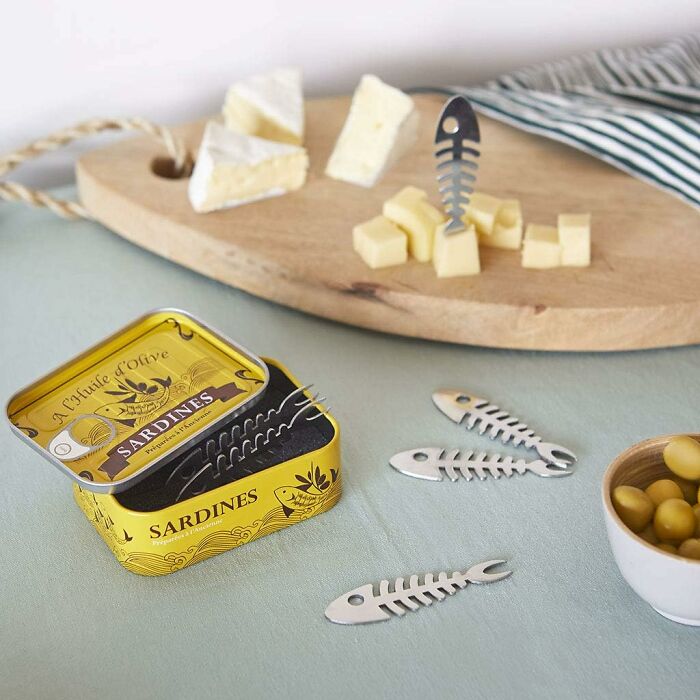 Food-shaped objects including sardine bone-shaped cheese markers on a table with cheese cubes and olives.