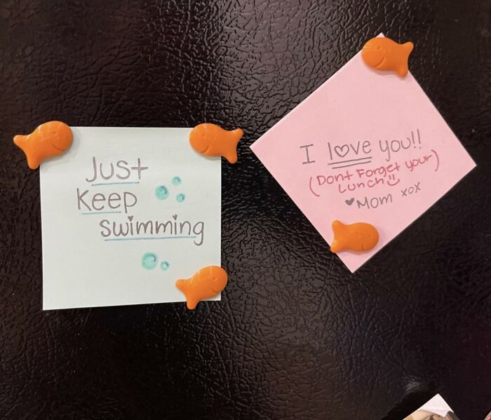 Orange fish-shaped magnets holding notes on a black fridge, showcasing creative food-shaped objects for decoration.