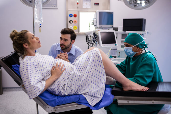 Doctor and partner assist a pregnant woman in labor at a hospital, focusing on a life-saving procedure.