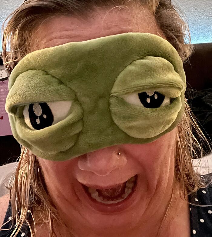 Person wearing a quirky green eye mask with large cartoon eyes, showcasing one of the unusual Amazon finds.