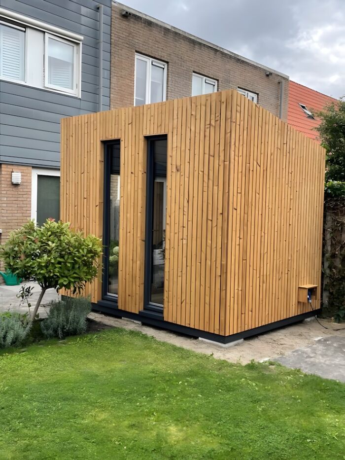 Modern wooden garden shed with vertical wood paneling and large glass doors in a backyard setting woodworking ideas.