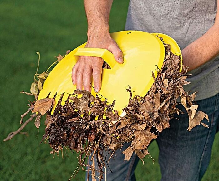 Person using a yellow leaf scooper tool, effortlessly clearing leaves from the lawn, showcasing chore-easing products.