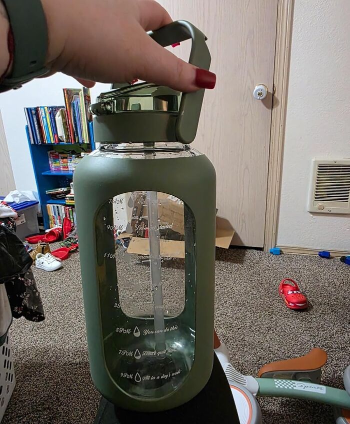 Hand holding a large green water bottle in a room, symbolizing a fresh start this spring with no-stress changes.