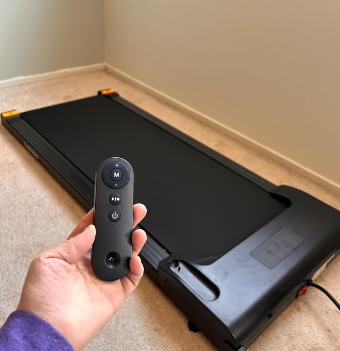 Hand holding treadmill remote control, symbolizing a fresh start with no-stress changes for spring fitness.