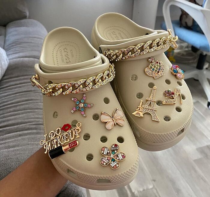 Beige Crocs adorned with colorful charms and gold chains for a fresh spring style change.