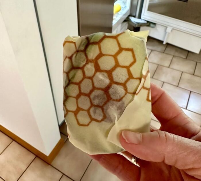 A hand holding a beeswax wrap, showcasing no-stress changes in kitchen storage options.