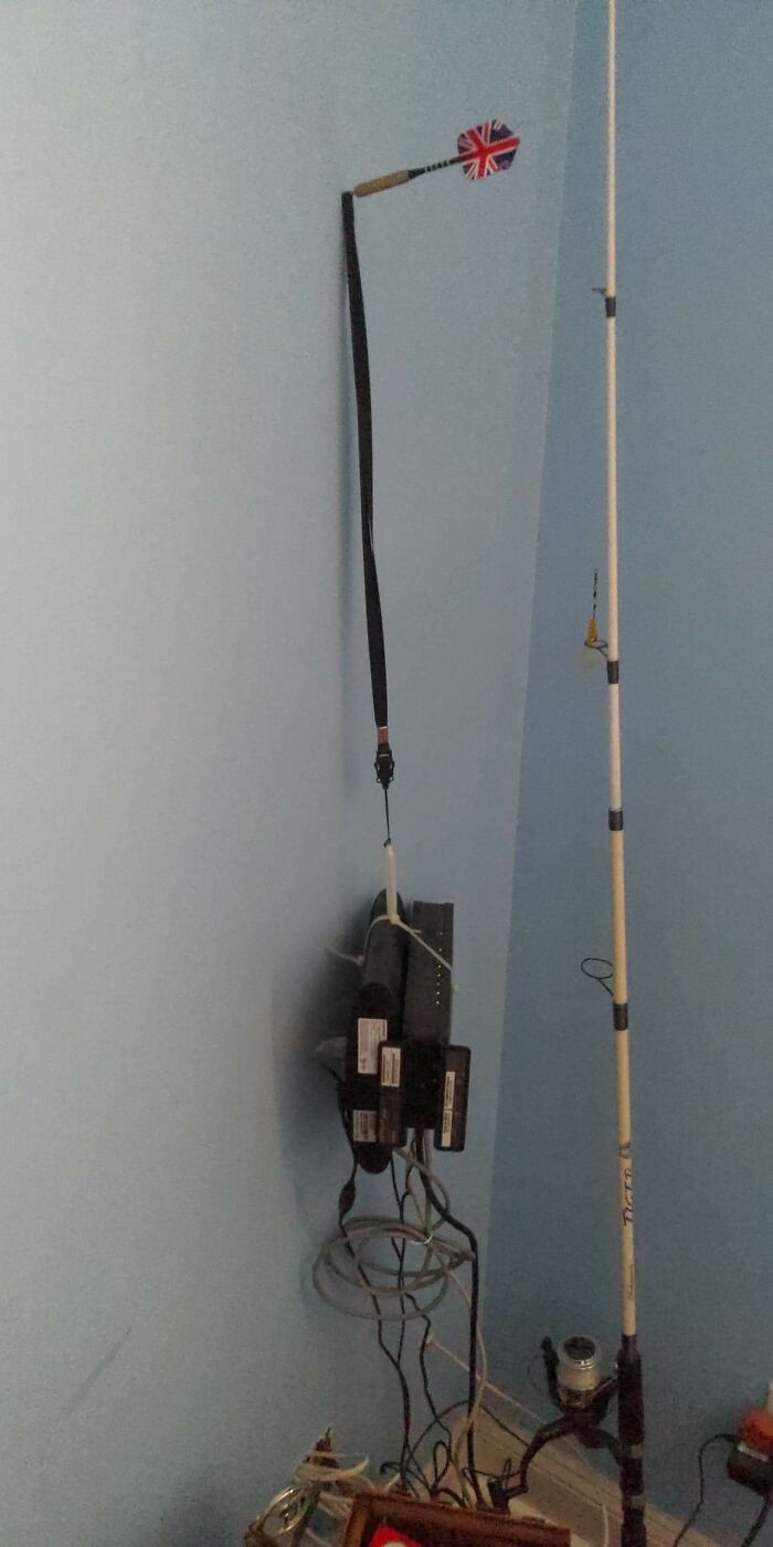 Failed repair attempt with poles, wires, and a dart in a room corner, illustrating DIY mishaps.