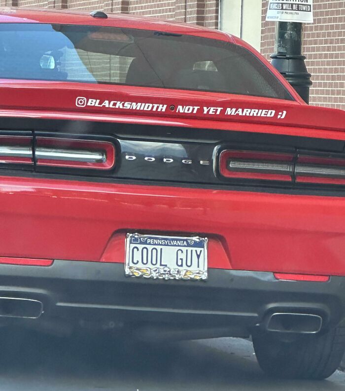 Red Dodge Challenger with "Not Yet Married" sticker and "COOL GUY" license plate, showcasing cringe behavior.
