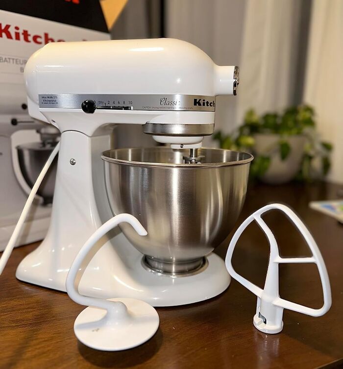 White stand mixer with metal bowl and attachments on a wooden table, representing items that last a lifetime.