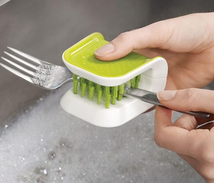 Hands using a green fork cleaning brush, a perfect daily tool for spotless utensils.