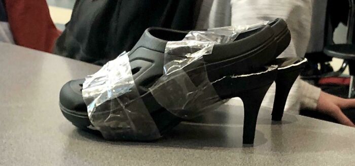 Failed repair attempt with tape holding a sandal to a high heel, creating an unusual footwear combination.