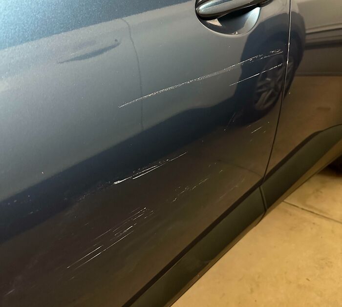 Car door with noticeable scratches, possibly indicating a horrible day for its owner.