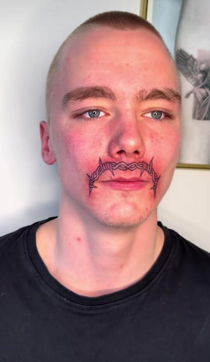 Close-up of a man with a hilariously bad tattoo resembling barbed wire above his lips.