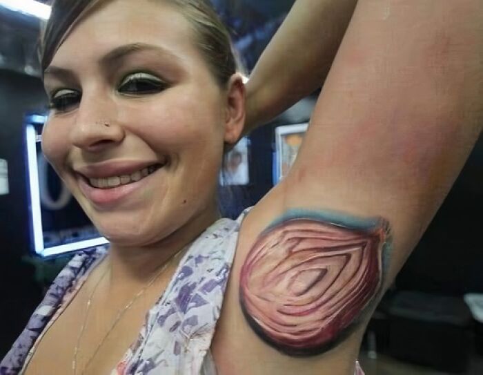 Woman smiling with a bad tattoo of an onion on her armpit, showcasing humorous body art.