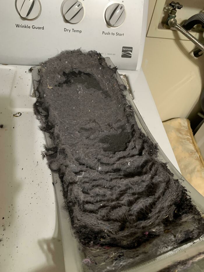 Dryer lint trap filled with lint, presenting a dangerous fire hazard in a laundry room setting.