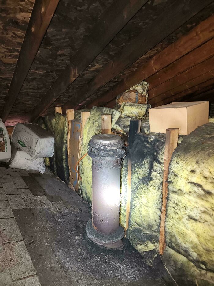 Dangerous insulation setup in attic with damaged pipe, highlighting potential fire hazard in home.