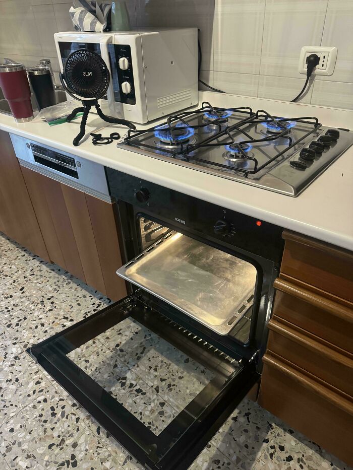 Gas stove with blue flames near oven and fan, illustrating a potentially dangerous kitchen setup.