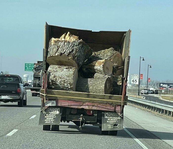 Camión transportando troncos grandes en una carretera, ilustrando un escenario potencialmente peligroso.