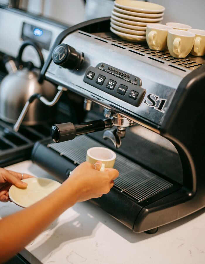 A person using an espresso machine, illustrating a moment of future prediction in coffee technology.