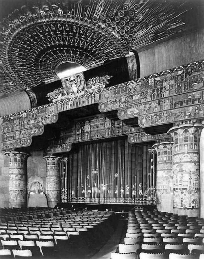 Ornate historic theater interior with Egyptian-themed decor, empty seats facing an elaborately decorated stage.