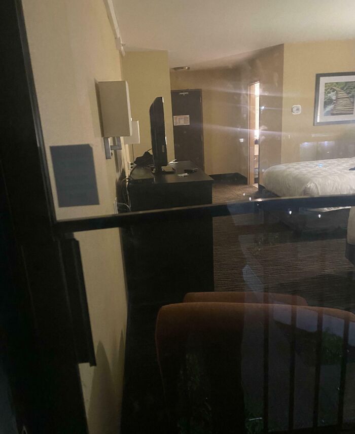 Hotel room viewed through a window, with locked door and TV, illustrating a horrible day scenario.