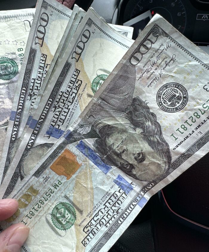 Holding several $100 bills, illustrating a turnaround from a horrible day scenario.