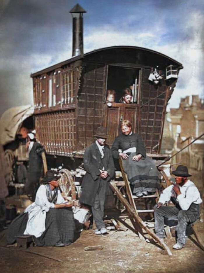 Historical photo of people gathered outside a vintage wooden caravan, showcasing 19th-century lifestyle.