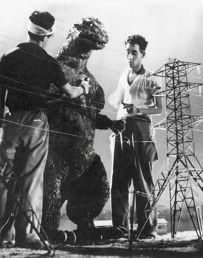 Filmmakers adjust a Godzilla model in a historical behind-the-scenes shot.