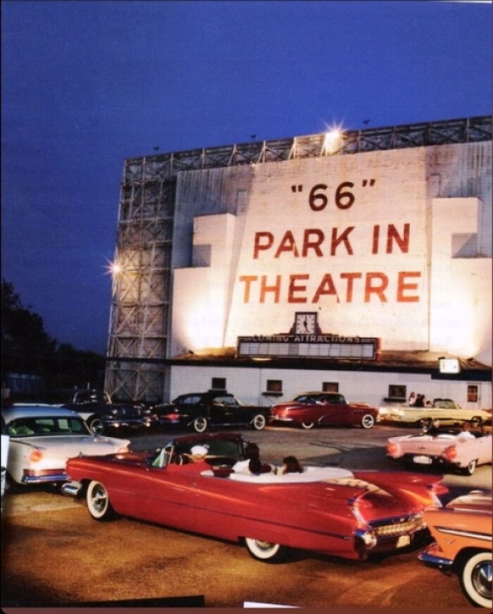 Drive-in theater with vintage cars parked in front, showcasing a nostalgic scene for history enthusiasts.