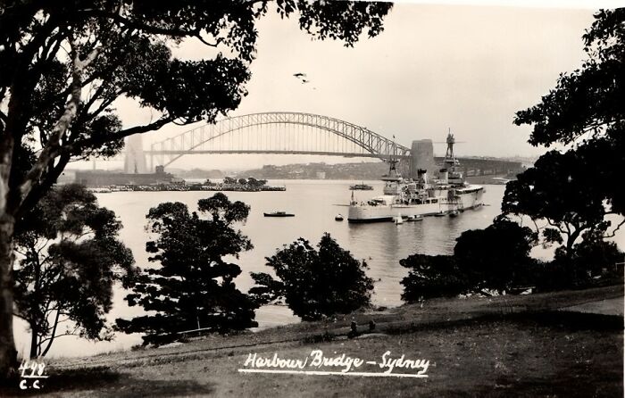 Black and white photo of Sydney Harbour Bridge and ships, ideal for history enthusiasts.
