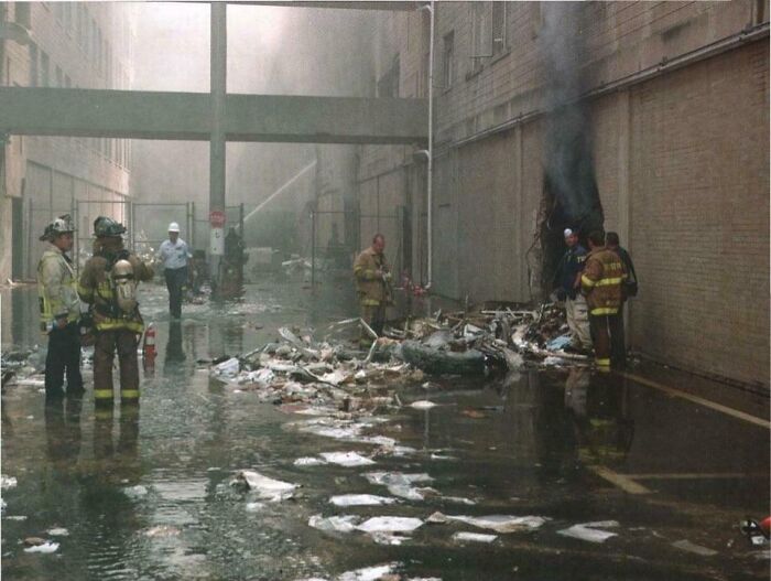 Firefighters inspecting debris in a flooded alley, offering a new perspective on famous events.