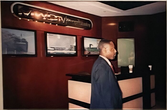Man standing in a dimly lit room with three screens on the wall, providing a new perspective on famous places.